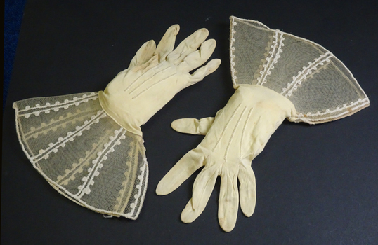 Cream gloves of nylon and stiffened net, embroidered at wrist with cream cotton