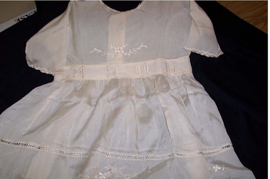 Cream silk baby's dress with round neck magar sleeves, opening down back of bodice with three press studs to waist. 