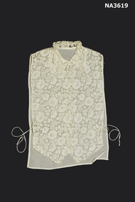 A cream lace front with five self fabric buttons below a collar with points. 