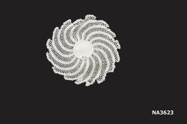 Small round white hand-crocheted doily with white damask centre. 