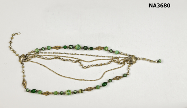 Necklace with six strands of green beads and silver decorations.