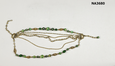 Necklace with six strands of green beads and silver decorations.