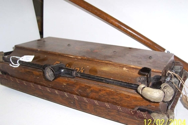 Carpet sweeper with wooden casing enclosing brush rollers. 