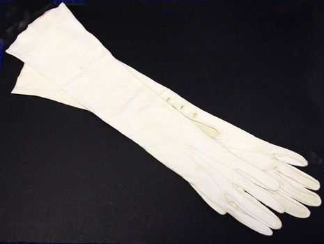  Pair of elbow length cream kid gloves, three pearl buttons at wrist
