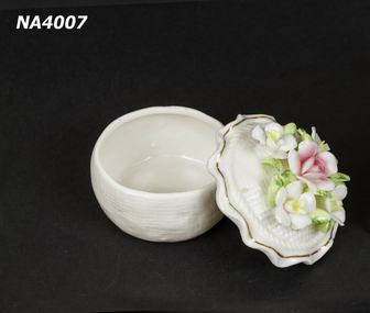 Cream china dish, with fluted lid and five china flowers and leaves arranged on top of lid.