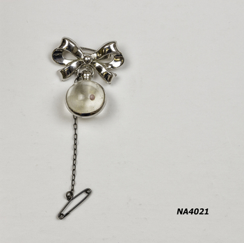 Silver bow with glass ball suspended from bow and silver metal band.