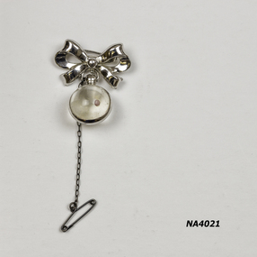 Silver bow with glass ball suspended from bow and silver metal band.