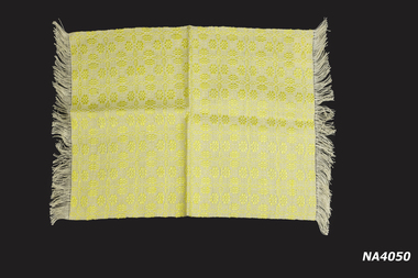 Yellow cotton handwoven place mat with fringing on two ends.
