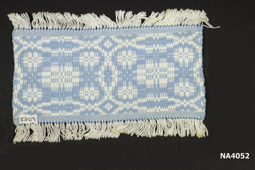 Cream and blue woven place mat with cream fringe.