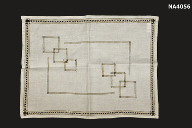 Cream linen place mat embroidered in brown drawn thread work.
