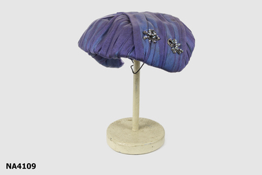 Brimless hat using blue/mauve nylon material lined with 'whitish stained' white material.