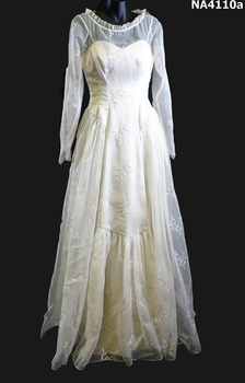 1958 Cream embroidered Nylon wedding dress. Fitted long sleeves to a point at waist, fastened with thirteen self covered buttons. 