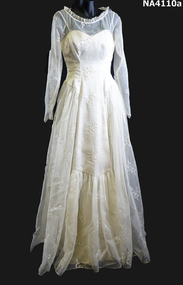 1958 Cream embroidered Nylon wedding dress. Fitted long sleeves to a point at waist, fastened with thirteen self covered buttons. 