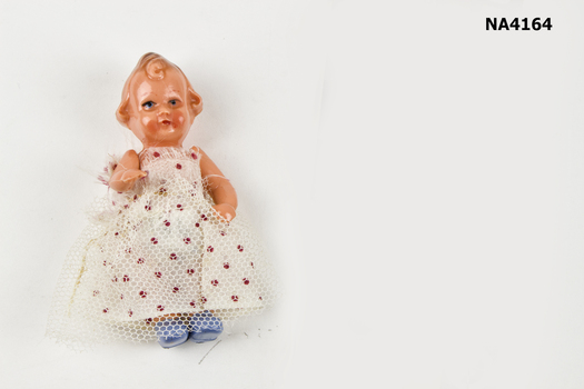 Small celluloid doll. Curly hair with blue shoes. Red and white skirt with tulle over skirt. 