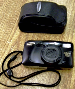  Black bakelite oval camera with black carry cord attached.