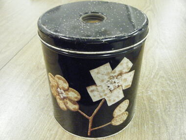 Black tin cannister with lid which has a recessed screw, knob hollow on top. 