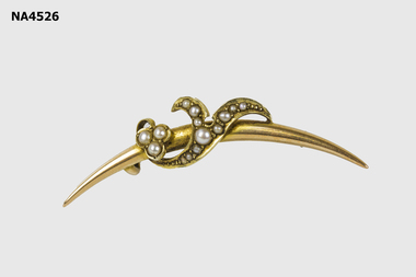  Curved gold bar with curled decoration inset with nine tiny pearls. 