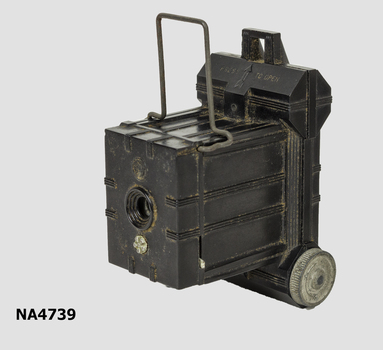 Small black camera with box like section at front and broader section at rear, to hold film.