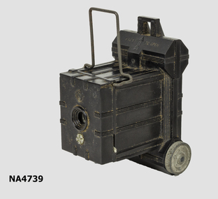 Small black camera with box like section at front and broader section at rear, to hold film.
