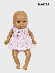 Plastic baby doll dressed in pink hand knitted dress and pants.