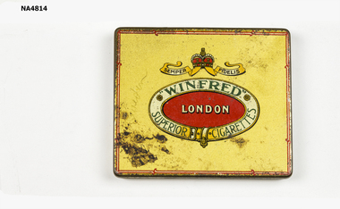 Gold coloured tin. A crown in red and gold on the top with a scroll with 'Semper Fidelis' printed on it. An oval shape below scroll outlined in gold with 'WINFRED' 'London' and 'Superior cigarettes'/ Inside on lid 'WINFRED' cigarettes printed within a scrolled outline. Below is printed ARDATH TOBACCO Co LONDON ENGLAND.