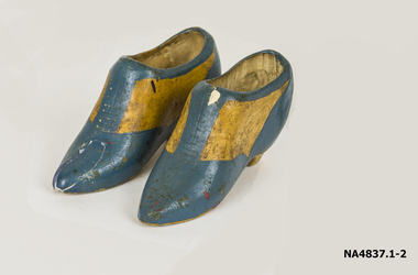 A pair of miniature dark fawn coloured pottery shoes.