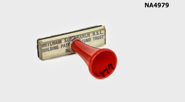 Rubber office stamp with clear plastic backing and red plastic handle.