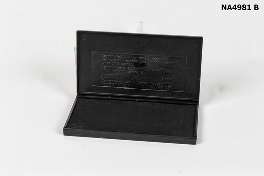 A  black plastic case containing a black ink pad. 