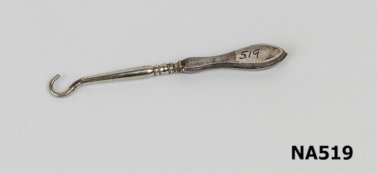 Small silver coated button hook used to catch buttons and pull them through eyelets of boots and shoes.