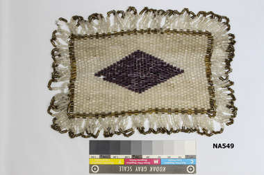 Table doyley made of glass beads. Brown edge with purple diamond in centre.