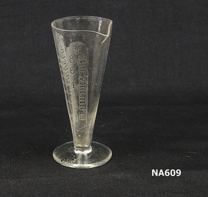 Glass measure for medical doses marked in fluid ounces and fluid drams