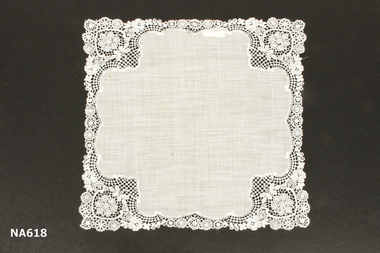 White linen handkerchief embroidered on each corner and around the edge