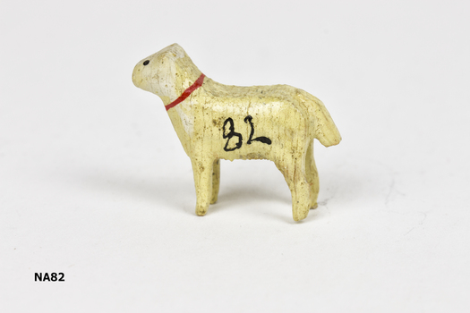 Tiny cream painted wooden dog with red collar