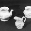 Cream china toy tea set with small gold pattern and edging. Comprises nine pieces - Two plates, cups and saucers, one milk jug, sugar pot with handles and tea pot