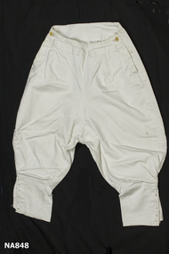 White cotton ladies riding breeches. Two back pockets and buttoned at waist and side. Lacing holes at bottom of legs.
