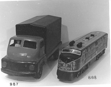 Large dark blue metal truck with red cabin and rubber wheels, white figure in cabin