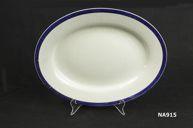 Oval white porcelain plate with dark blue stripe.