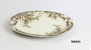 White china oval dish with dark brown pattern possibly of wattle