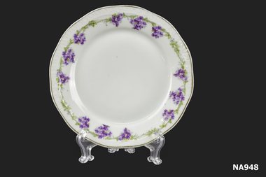 White china plate with lilac and green decoration on border.