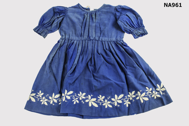 Dark blue child's dress with white embroidered flowers around hem.
