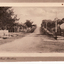 Black and white postcard titled 'Blackburn Road, Blackburn'.  Scene shows Blackburn Road looking  South from railway gates.  Shop on one corner.  Unmade road.