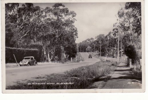 lack and white postcard of Blackburn Road with two cars in photo. 