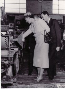 Black and white photo of Prince and Princess of Luxembourg inspecting machinery at weaving mills