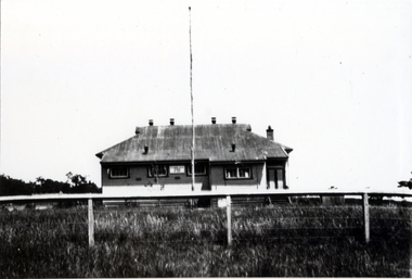 Black and white photo of Blackburn South State School, a wooden building with flag pole in front.