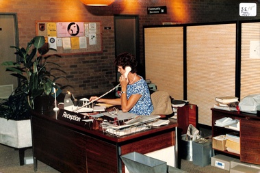 Coloured photo of June Kennon at Reception Desk.
