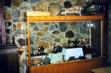 Display in large cabinet in Local History Room of Sewing Machines and related sewing objects.