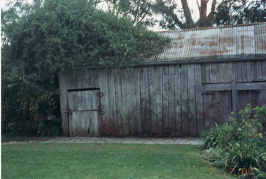 Coloured photograph of exterior of barn showing horseshoes as hinges on door.