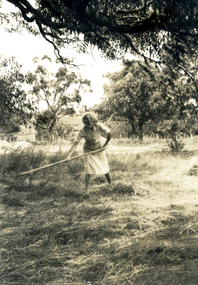 A girl raking hay in the grounds of the Forest Hill Residential Kindergarten.