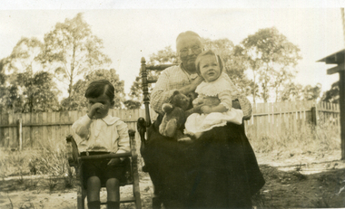 Elderly woman sitting on a chair holding a female child (Alison Till) on her lap. 