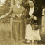 Two women standing in front of a wire fence with trees in the background. 